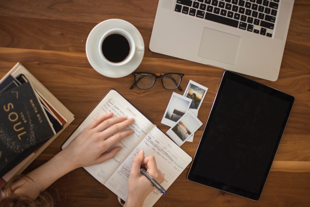 person planning a retreat with laptop, polaroid photos, ipad and coffee cup 